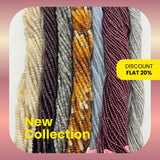 Multiple strands of gray and garnet gemstone beads in rondelle, drop, pipe, coin, drum, and oval shapes on a white background.