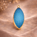 Blue druzy pendant gold bezel marquise shape on silk fabric, sparkling teal crystal gemstone jewelry