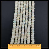 May include: Strands of faceted opal beads in various shapes and sizes. The beads have a milky white base colour with flashes of iridescent colour. A ruler is placed at the bottom of the image, measuring up to 40.6 cm.