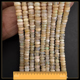 May include: Strands of faceted, light-coloured opal beads. The beads are a mix of cream and pale yellow, with subtle iridescent flashes. The ruler at the bottom shows a length of 40.6 cm. These beads are suitable for jewellery making.