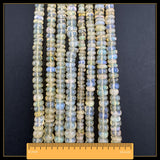 May include: Strands of opal beads in shades of yellow, blue, and white. The beads are round and polished. A ruler shows the beads are approximately 40.6 cm in length.