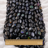 Close-up of natural Ethiopian black opal oval smooth beads — Welo black opal cabochon with vivid blue teal fire flash, per strand gemstone beads lot
