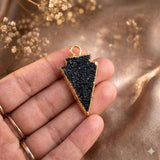 Hand holding Black Druzy Arrowhead Pendant against golden 
bokeh background — showing actual size of Handmade Gothic 
Jewelry 24K Gold Electroplated Druzy Gemstone Pendant