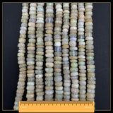 May include: Strands of faceted opal beads in cream, white, and pale green hues. The beads are arranged in vertical rows, with a ruler at the bottom indicating a length of 40.6 cm. The beads have a subtle iridescence.